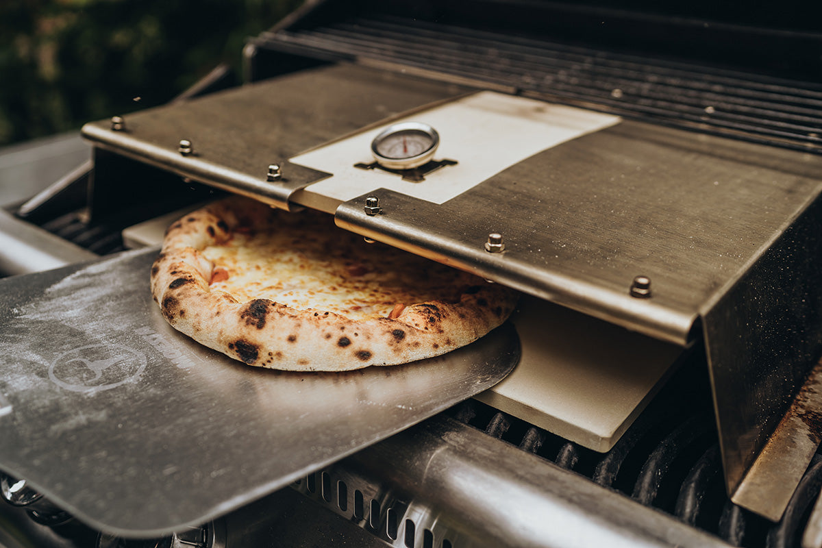 Gebackene Pizza auf dem Pizzaschieber vor der Öffnung des LORENZO Pizzacovers