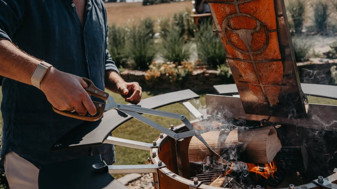 Die BOA Grillzange von MOESTA legt einen Holzscheit in den BANDIT 2.0 Fireplace nach