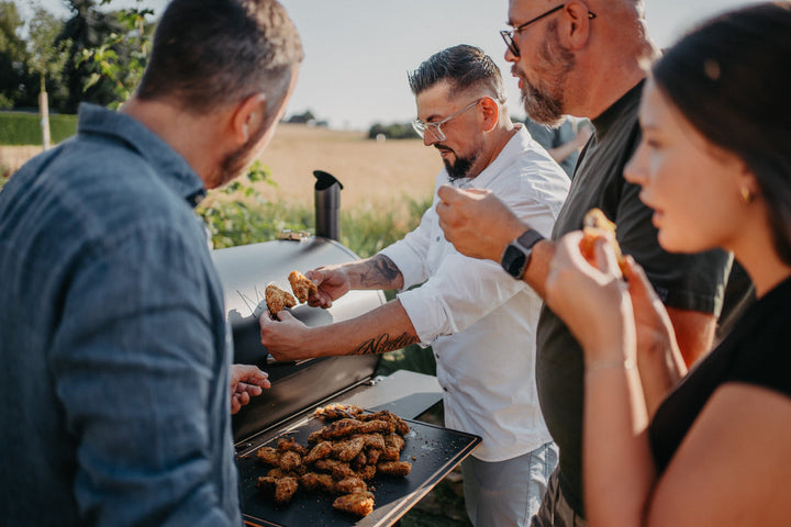 Freunde genießen gemeinsam Grillgut direkt am MOESTA SHERIFF