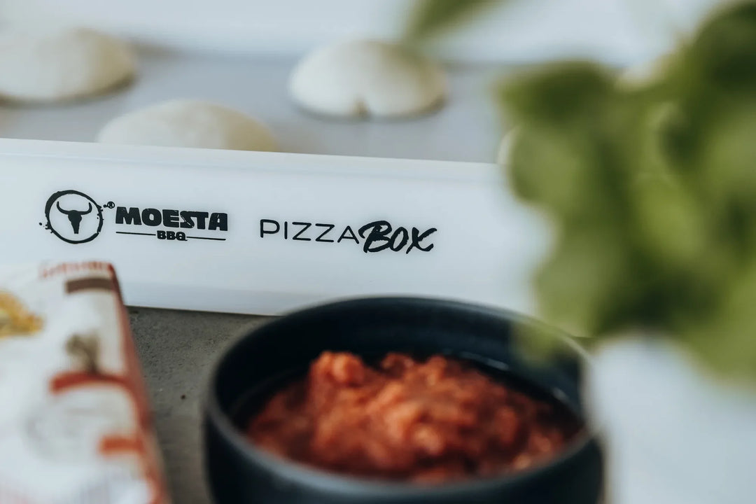Pizzateiglinge in der MOESTA PizzaBox, davor eine Schale Tomatensauce