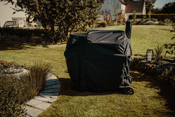SHERIFF 2.0 Pelletgrill unter der schwarzen MOESTA Abdeckhaube im herbstlichen Garten