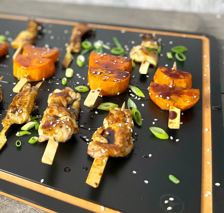 Glasierte Yakitori-Spieße mit Hähnchen, Süßkartoffel und Kräuterseitlingen auf einem Brett