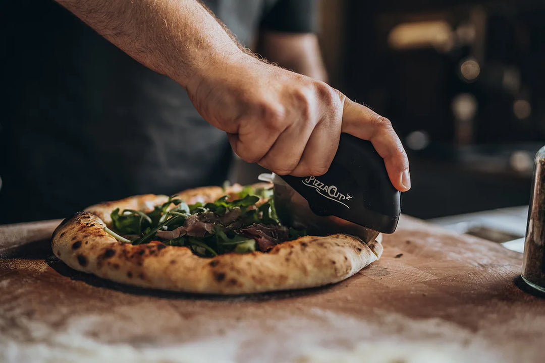Pizza mit Rucola wird mit dem PizzaCut geschnitten