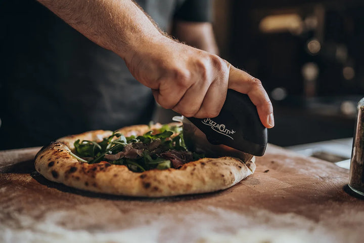 Pizza mit Rucola wird mit dem PizzaCut geschnitten
