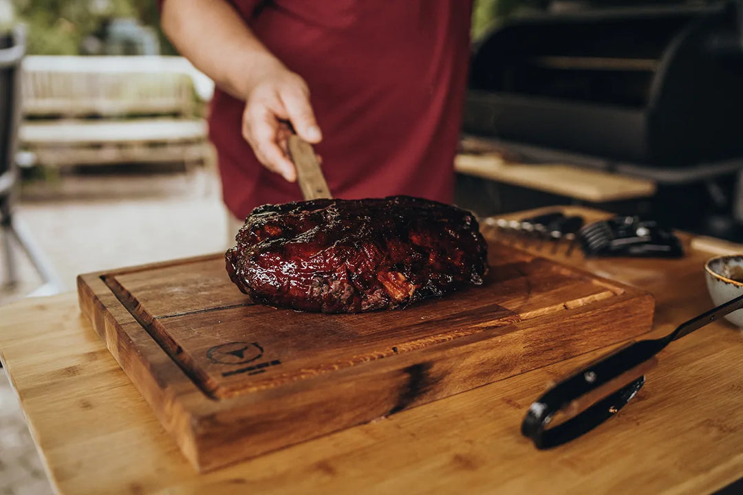 Pulled Pork mit dunkler Kruste auf dem Holzbrett