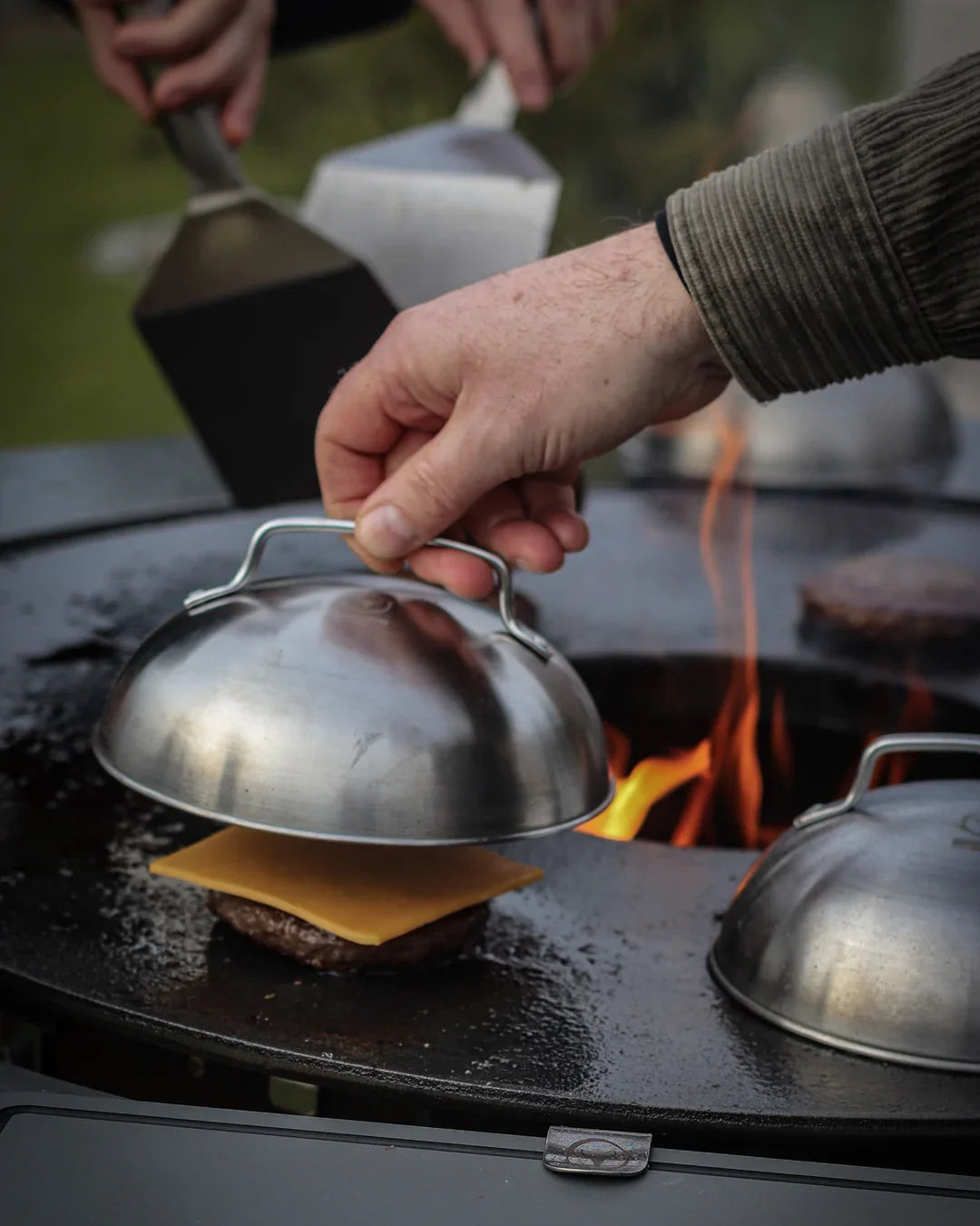 Ein BurgerCover wird über einen Burger mit Käse auf der BBQ Disk am MOESTA BANDIT gesetzt.