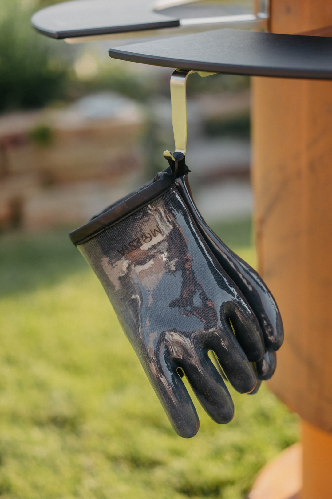 Hitzehandschuhe am optionalen Edelstahl-Haken unter einer Ablage des MOESTA Bandit 2.0