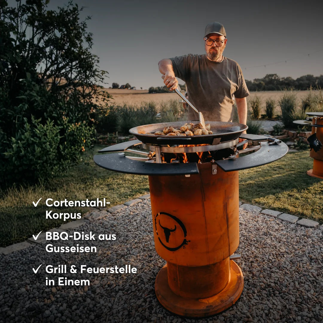MOESTA-BBQ BANDIT 2.0 mit Cortenstahl-Korpus und BBQ-Disk aus Gusseisen beim Grillen im Garten.
