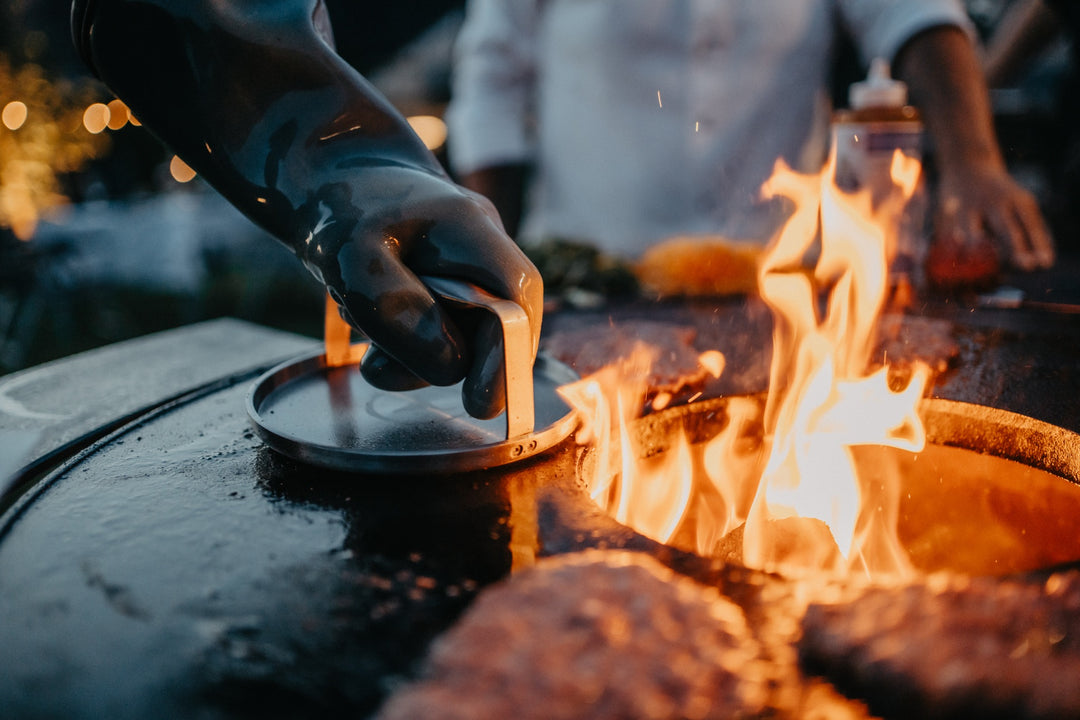 Burger werden mit einer Burgerpresse auf der BBQ Disk am offenen Feuer gebraten. Die Presse ist optionales Zubehör.