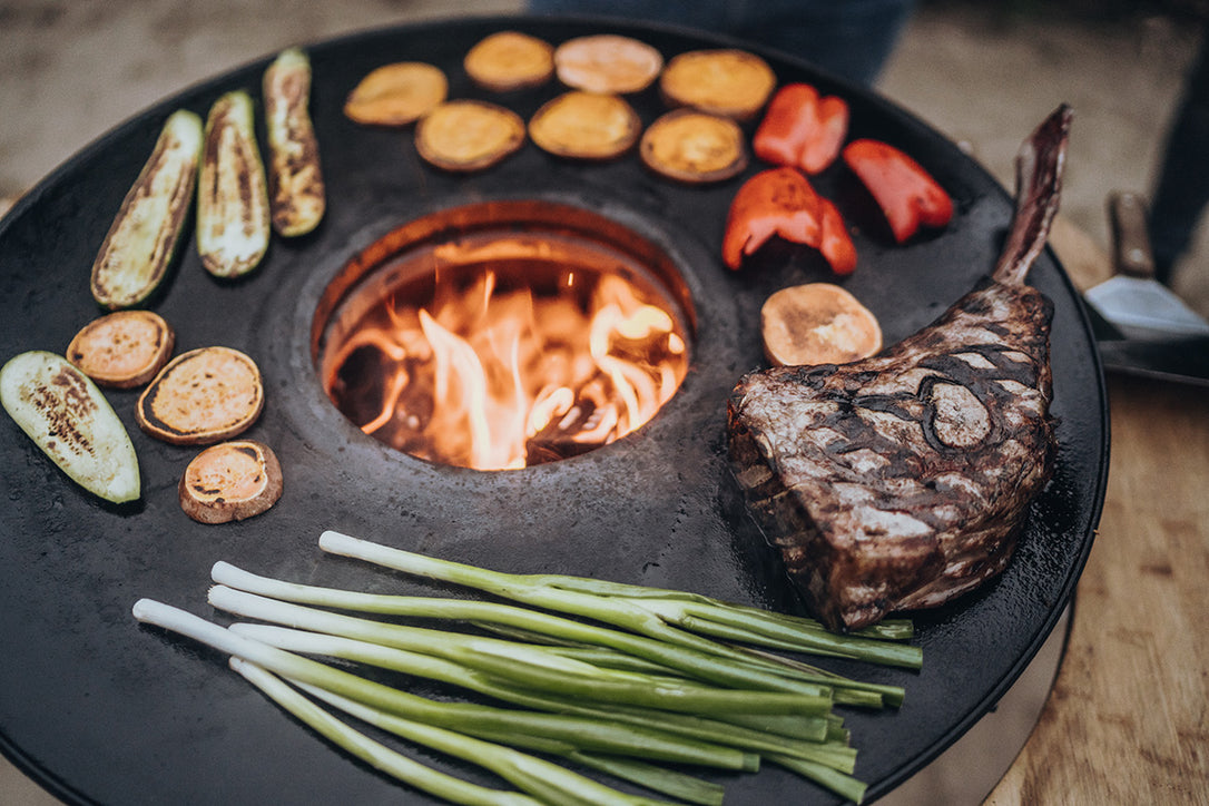 Steaks und Gemüse auf der gusseisernen Barbecue-Disc.