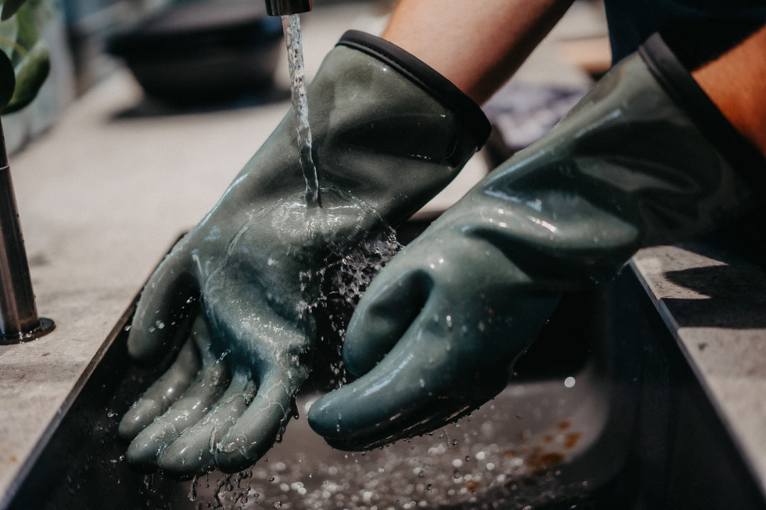 Die Silikonoberfläche der HEATPRO Handschuhe wird unter fließendem Wasser abgewaschen.