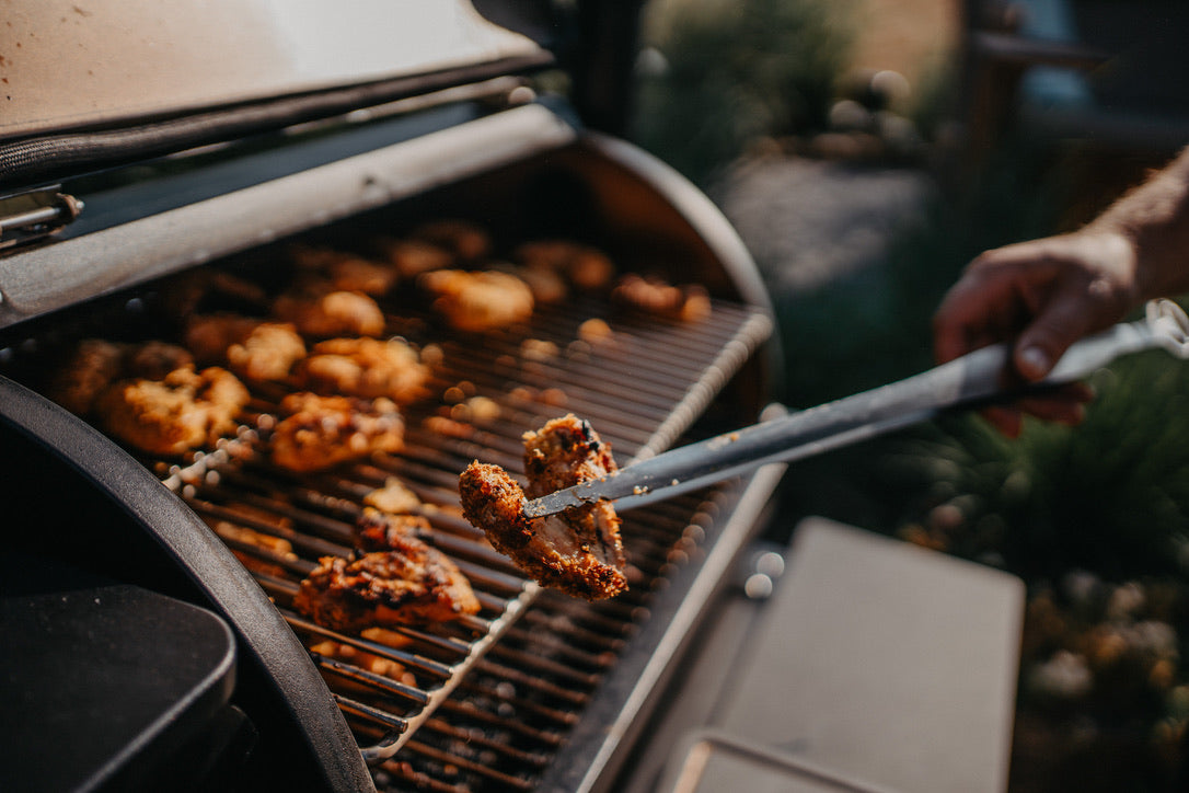 Knusprige Chicken Wings werden mit der Grillzange aus dem SHERIFF genommen