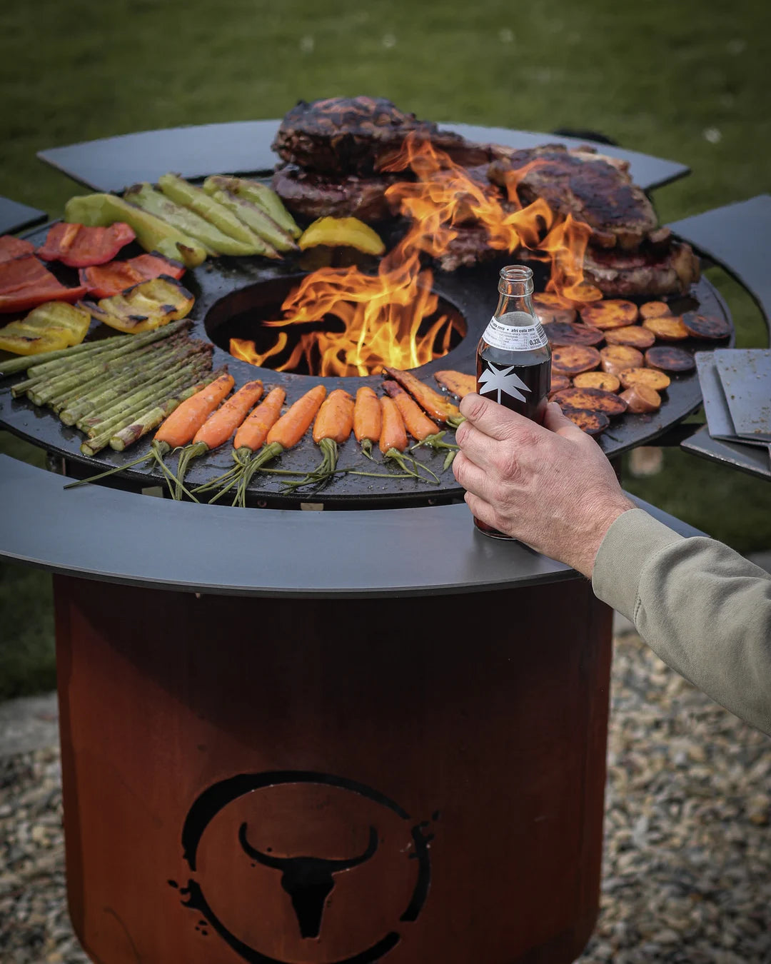 BANDIT 2.0 mit voll belegter BBQ Disk rund um das Holzfeuer im Garten